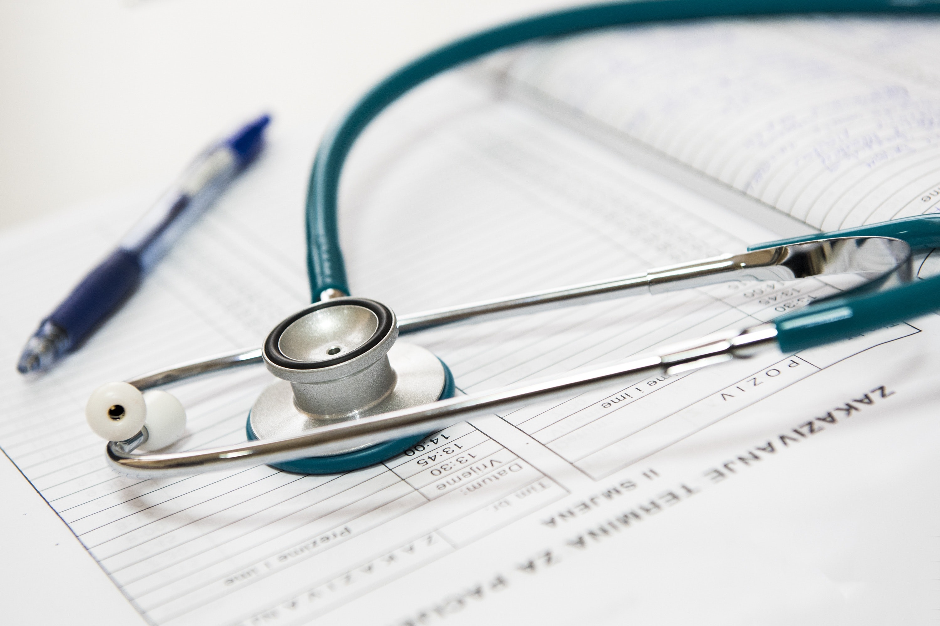 A stethoscope and a pen on a clipboard