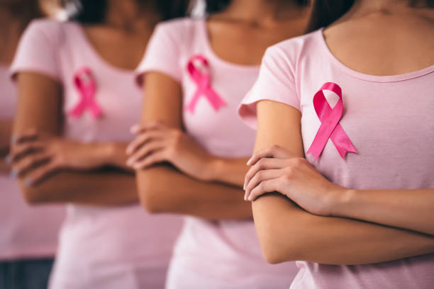 a group of women wearing pink with pink ribbons to symbolize Breast cancer awareness month in October for screening mammograms and self breast exams. 