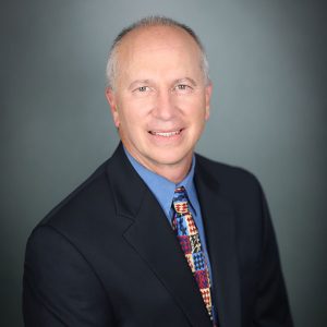 Carmen M. Todoro, M.D., a man with short, grey hair, wearing a black suit.