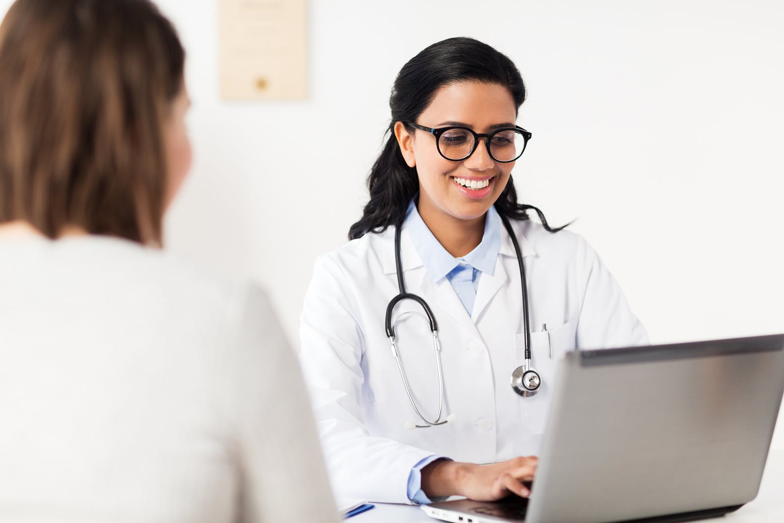 a female obgyn on a computer alongside a female patient