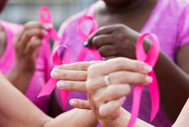 A group of women holding pink ribbons to symbolize Breast Cancer awareness month in October to raise awareness for screening mammograms and self breast exams. 