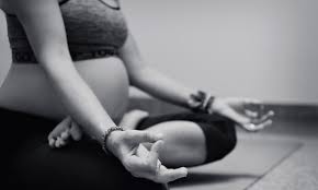 A pregnant woman sitting in a yoga pose