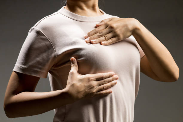 Adult woman do breast self exam in pink t-shirt